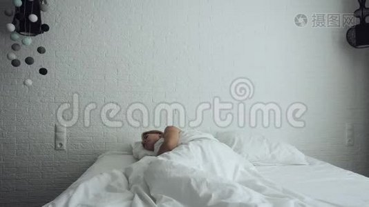 女人醒来在舒适舒适的床上伸展和起床。视频