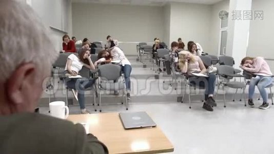 一群学生在大学里睡觉，教授坐在桌子旁。视频