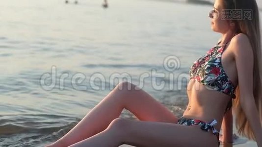 穿着泳衣的年轻迷人的女孩赤着脚跌入海浪中。视频