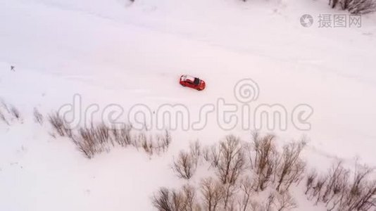 橙色的车骑在冬天的雪道上，俯视着。视频