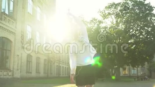 快乐的年轻人站在大学大楼前看着相机。 年轻人庆祝她的毕业典礼。 太阳。视频