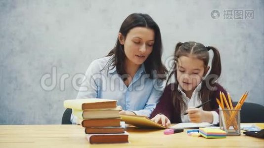 年轻的妈妈帮孩子写一堂课，或者让女儿和妈妈都学会写，有一个小女孩视频