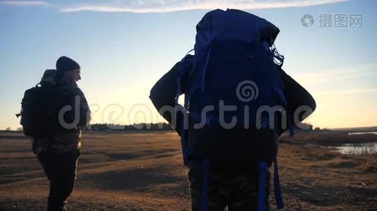 两位生活方式的游客一起背着背包，慢动作行走，在阳光的照射下走着剪影视频