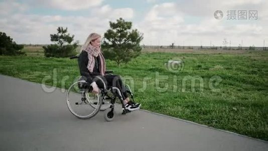 阳光明媚的一天，快乐的年轻女子在公园里坐轮椅旋转着身体视频
