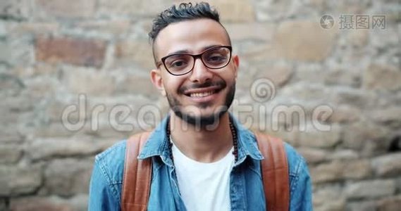 有魅力的年轻阿拉伯人微笑着看砖墙附近的摄像机的画像视频