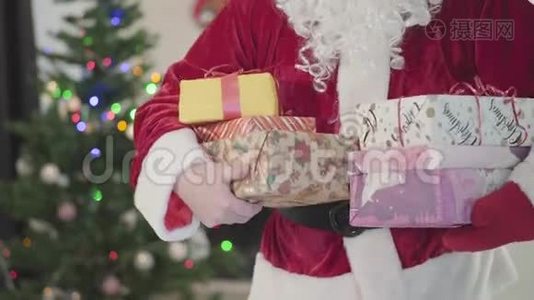 白胡子的成年白种人，穿着圣诞老人服装，在圣诞树的背景下带着礼品盒搬家视频