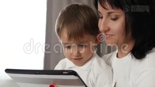 家庭肖像。 母子俩带着情绪看着平板电脑的屏幕：快乐，快乐，有趣..视频