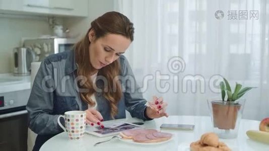 快乐的女人吃健康的早餐。 厨房用平板电脑的女性视频