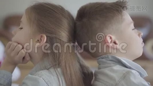 特写肖像，双胞胎男孩和女孩坐在客厅的地板上，背对着对方生气。 兄弟姐妹视频