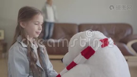 肖像可爱的女孩玩玩具北熊，给他戴上皇冠，她的孪生兄弟跳在沙发上视频