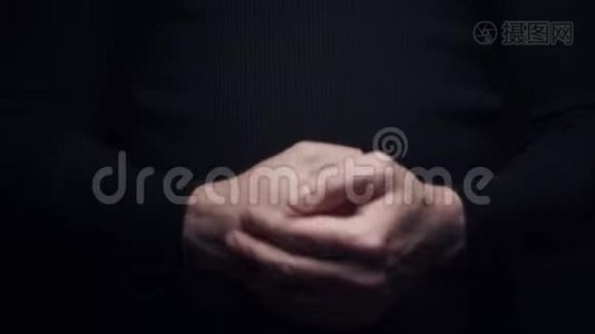 特写镜头的人用手掌击打他的拳头，在黑色背景上隔离视频
