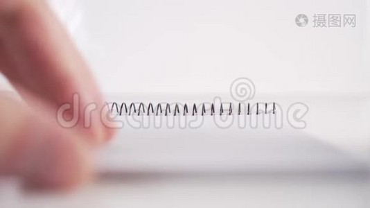 一个人慢慢地从一个垂直的笔记本上翻阅，白色背景上挂着一个螺旋形的黑色页面视频