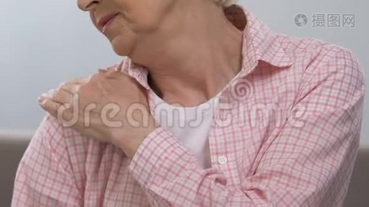 老年妇女按摩疼痛的肩膀，患有关节疾病，健康视频