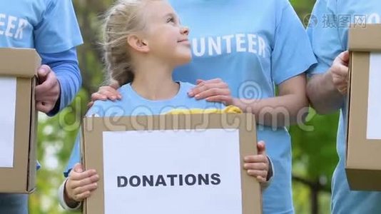 成人志愿者团队，带着孩子拿着捐款箱，微笑着，慈善视频