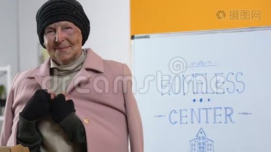 可怜的无家可归的妇女，穿着捐赠的温暖衣服，在支持中心寻找相机视频