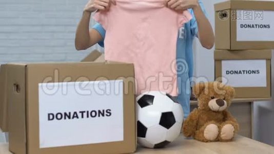 女士自愿把孩子们的东西放进盒子里，微笑着对坎姆，帮助孤儿院视频