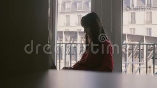 有魅力的成功自由职业女性，在美丽的巴黎公寓窗口度假时使用笔记本电脑。视频