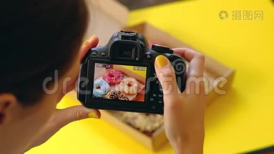 女人`手拿着盒里美味甜甜圈的照片相机拍照。视频