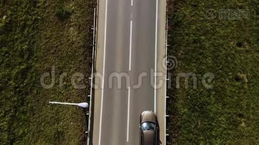 鸟瞰孤独的棕色SUV汽车在两片田野之间的道路上行驶。 两条车道的路上有车。视频