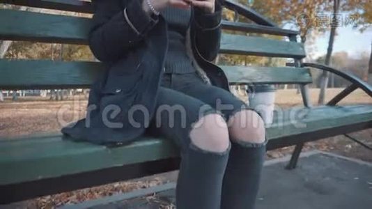 公园里坐在长凳上吃汉堡的女孩。 穿着夹克和帽子的女孩视频