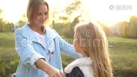 可爱的女人和她成年的十几岁的女儿互相拥抱，站在秋天公园的中间。 户外肖像画视频
