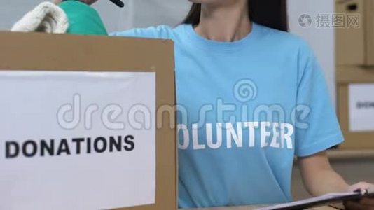 女青年志愿者透过盒子里的捐赠衣物寻找微笑的慈善机构视频