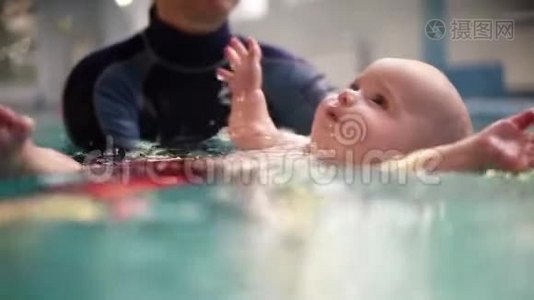 教练或妈妈教宝宝在游泳池游泳.. 婴儿躺在背上，学会保持平衡，继续前进视频