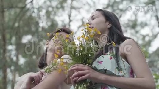 两个美丽的女人站在森林里，开着令人惊叹的野花。 慢动作。视频