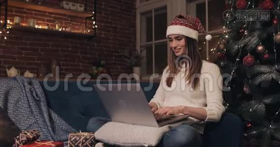 戴着圣诞帽、坐在家中圣诞树旁的年轻白种人女孩微笑背景使用她视频