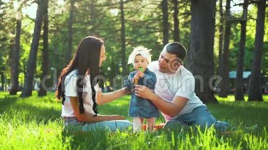 幼儿站在绿草上，她的父母支持她视频