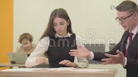肖像年轻的女秘书和她的老板坐在办公室里。 那个男人纠正了那个女孩的报告。 办公室视频