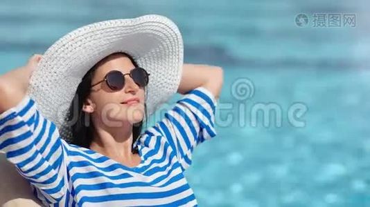 放松微笑时尚女性在游泳池附近享受日光浴，享受暑假视频