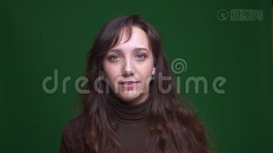年轻的黑发女学生的肖像在绿色背景上使面部手势被激怒和困惑。视频