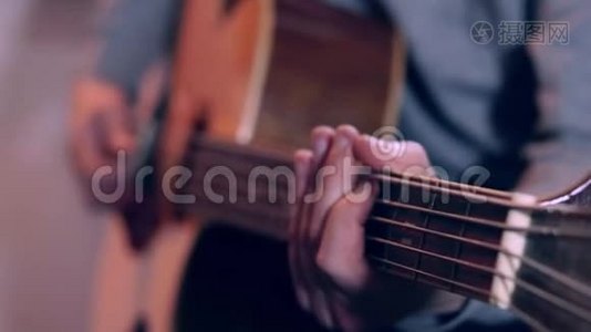 吉他手按着吉他的琴弦，用慢动作合上男人的手指在吉他上弹奏音乐。视频