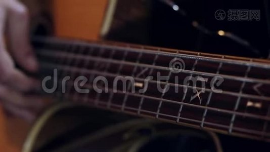 吉他手按着吉他的琴弦，用慢动作合上男人的手指在吉他上弹奏音乐。视频