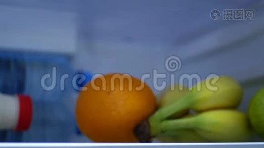 男子打开冰箱门，放入橙色柠檬和一瓶果汁视频