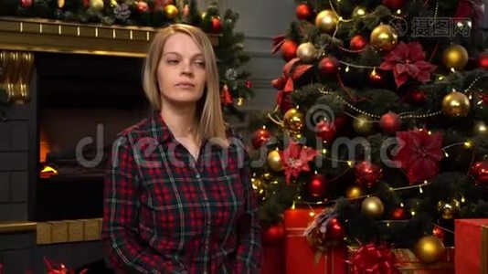 一个坐在圣诞树旁的漂亮金发女郎送礼物视频