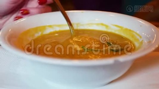 汤的特写。 女人在咖啡馆里吃白色盘子的汤匙。视频