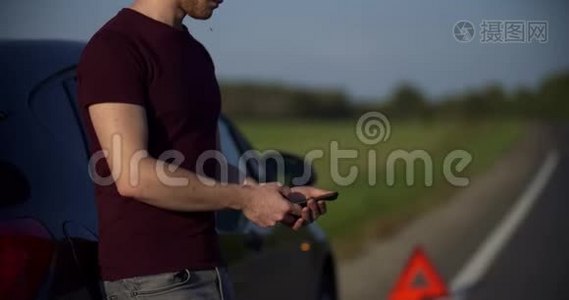 鹤射中年轻人的画像看着电话里的东西，路上一辆破车在车架上视频