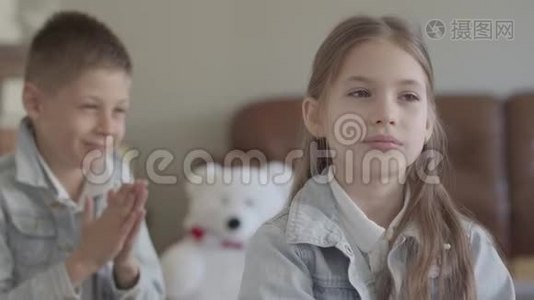 肖像可爱的孪生兄弟淘气的男孩在舒适的客厅里拉着他可爱的妹妹的头发，微笑着视频