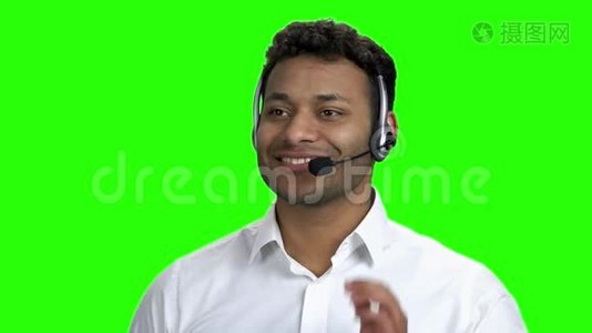 笑容满面的黑皮肤男人，戴着绿色屏幕上的耳机。视频