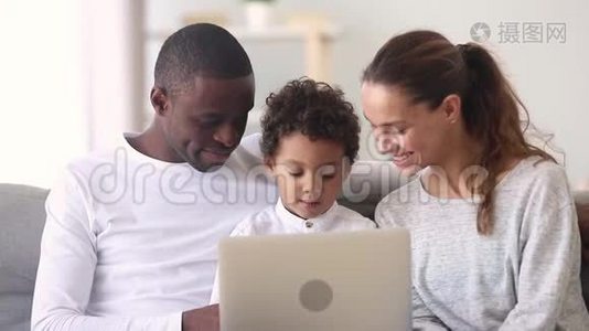 快乐的跨种族家庭爸爸妈妈和小儿子使用笔记本电脑视频