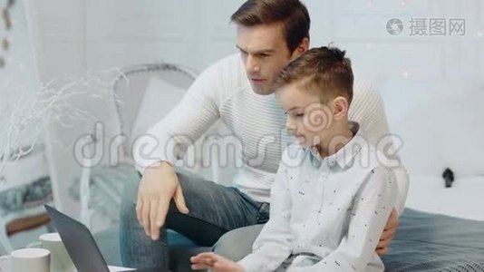 微笑的父子在豪华住宅的笔记本电脑上聊天。视频