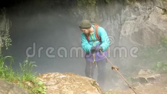 在深垂的洞穴隧道里，说话者用绳子往下走. 库存录像。 人类徒步旅行者发现未知视频