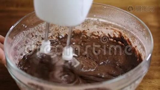 女性手的特写将水倒入巧克力面糊中。视频