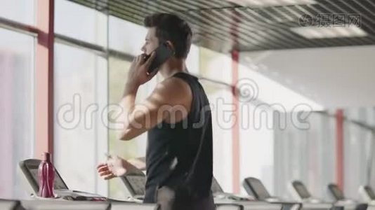 健身俱乐部里的运动员在跑步机上用手机说话。视频