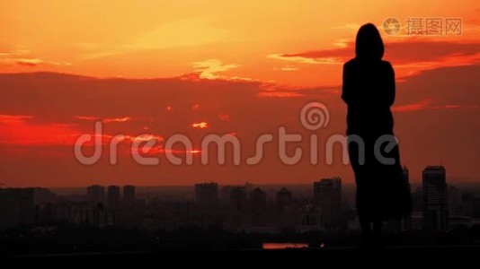 后景，站在室外的妇女，可以欣赏日落的城市景色视频