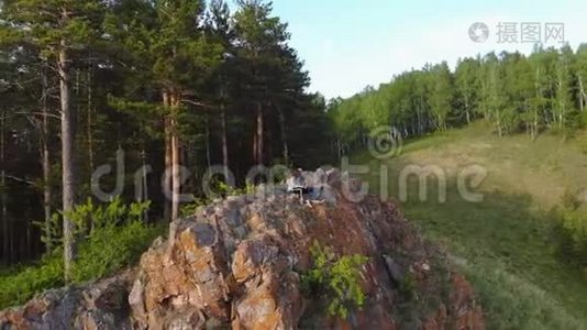 一对年轻夫妇坐在悬崖边欣赏美丽的景色。视频