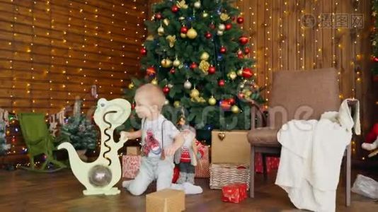 带玩具恐龙的小男孩在圣诞树附近。视频