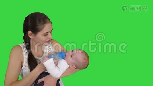 母亲抱着婴儿，用绿色屏幕上的瓶子喂婴儿，铬键。视频